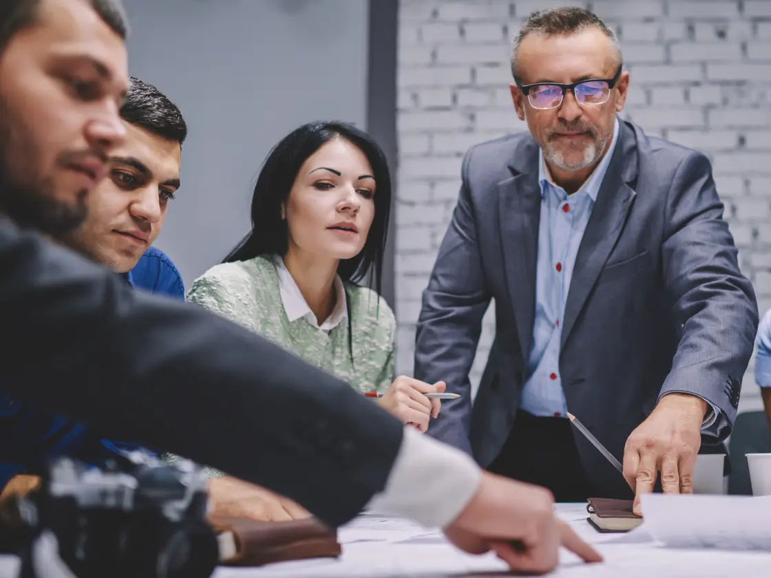 An experienced operator working through a plan with a small team around a table