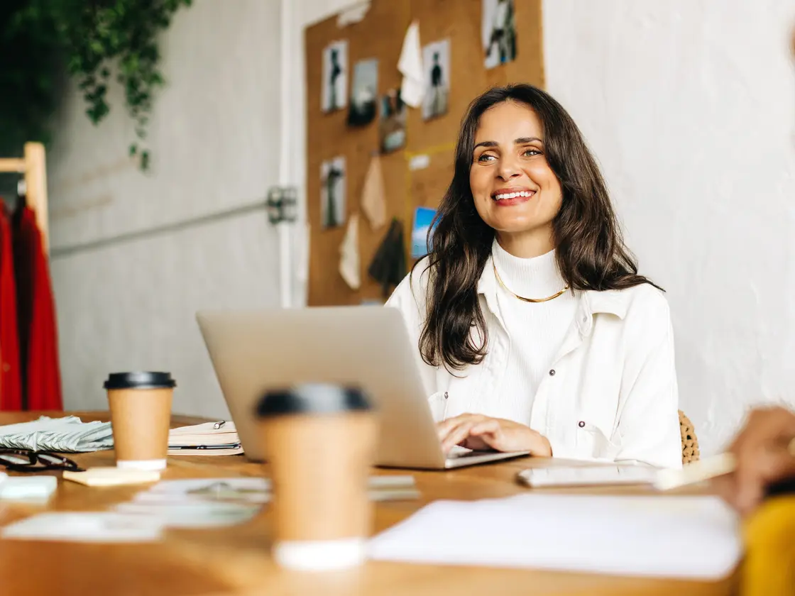 A business owner smiling at her laptop during a working session with her team