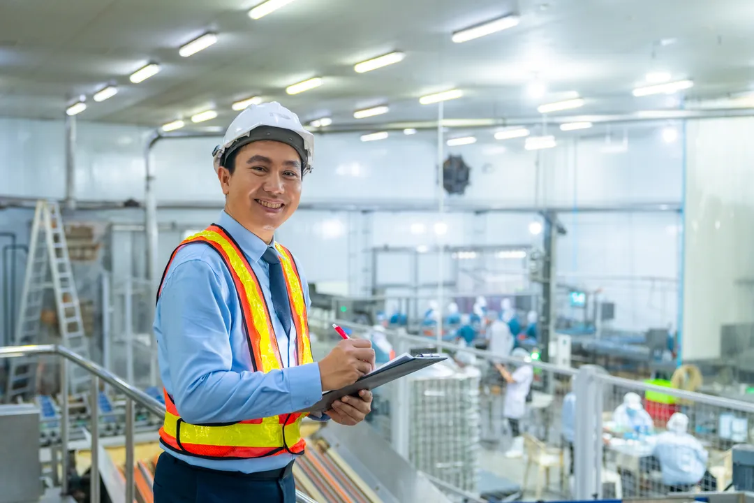 A food factory owner smiling proudly in front of a new factory