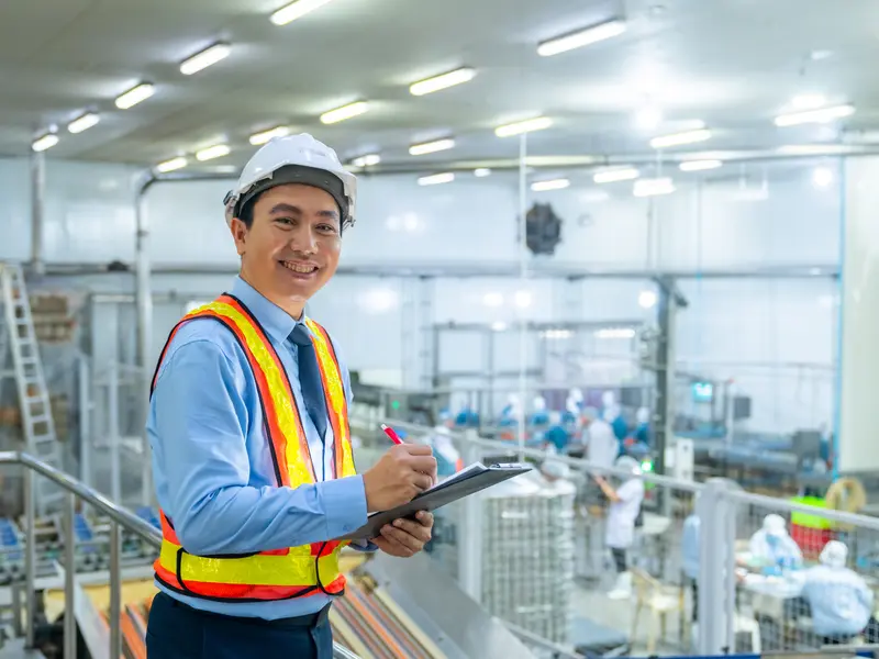 A business owner overlooking his production floor, clipboard in hand