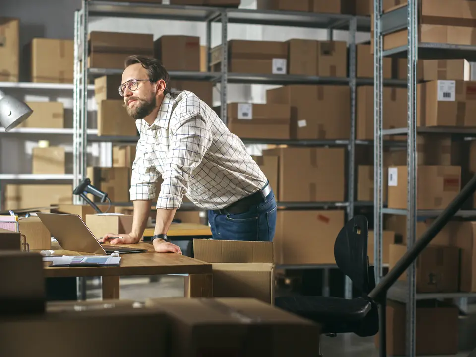 A business owner among the shelves of his warehouse, working out what the plan was