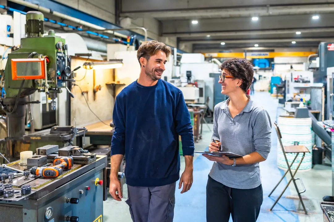 A manager and employee in a factory, considered and grounded with hand on chin