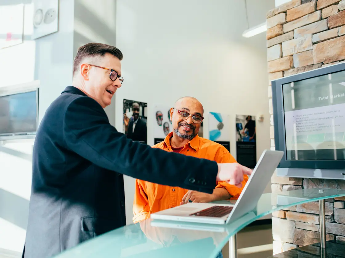 An experienced operator talking a team member through the numbers on a laptop