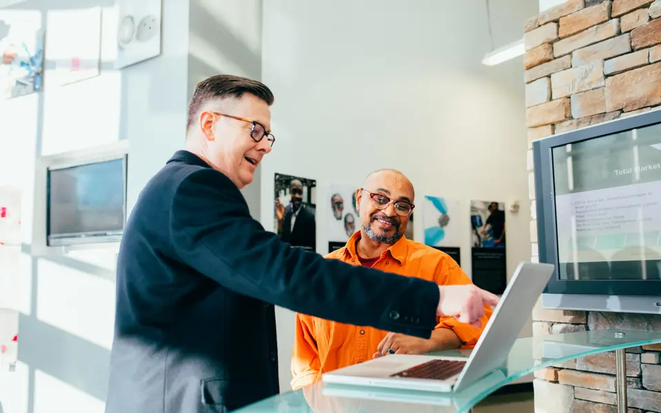 An operator talking a team member through the numbers on a laptop